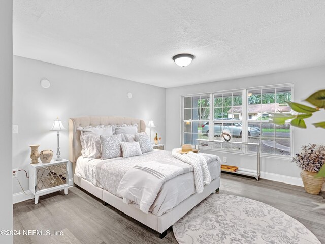 bedroom with a textured ceiling and wood-type flooring