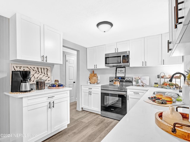 kitchen with stainless steel appliances, light countertops, a sink, and white cabinetry