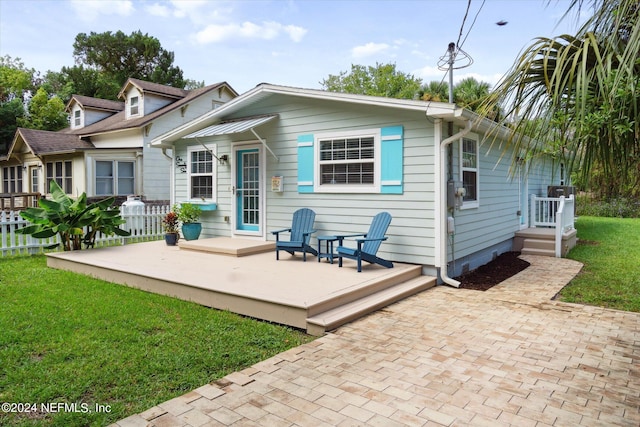 back of property featuring a yard, a wooden deck, and a patio