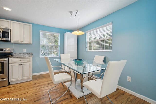 dining area featuring a textured ceiling and light hardwood / wood-style flooring