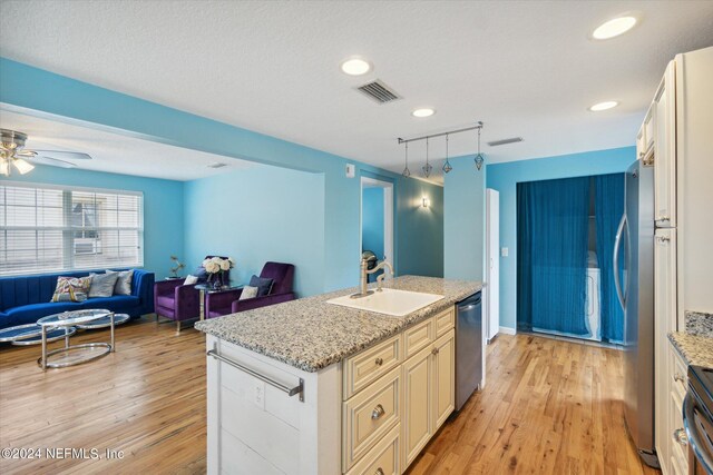 kitchen with light stone counters, light hardwood / wood-style flooring, ceiling fan, and sink