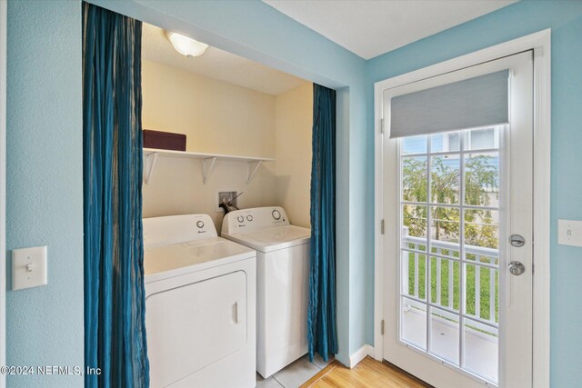 clothes washing area with separate washer and dryer and light wood-type flooring