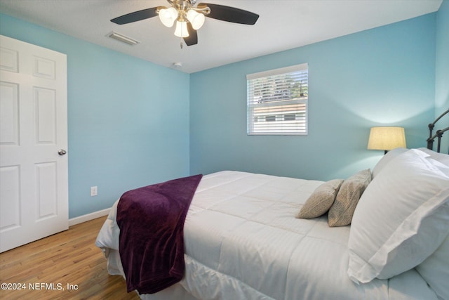 bedroom featuring a ceiling fan, baseboards, visible vents, and wood finished floors