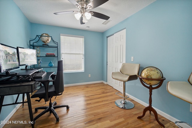 home office featuring a ceiling fan, wood finished floors, visible vents, and baseboards