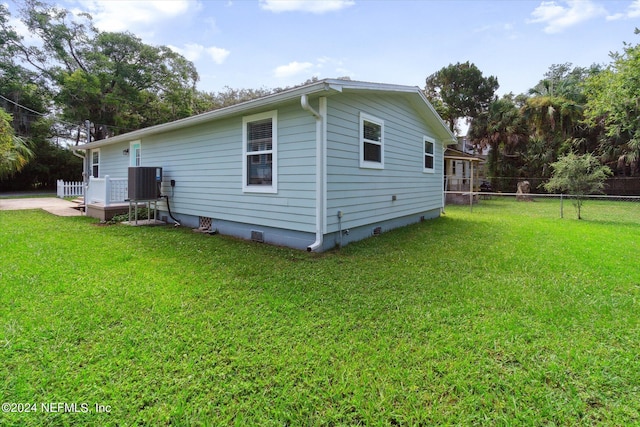 view of side of property with crawl space, fence, cooling unit, and a yard