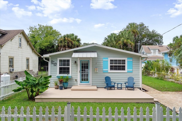 back of house featuring a fenced front yard, cooling unit, and a lawn