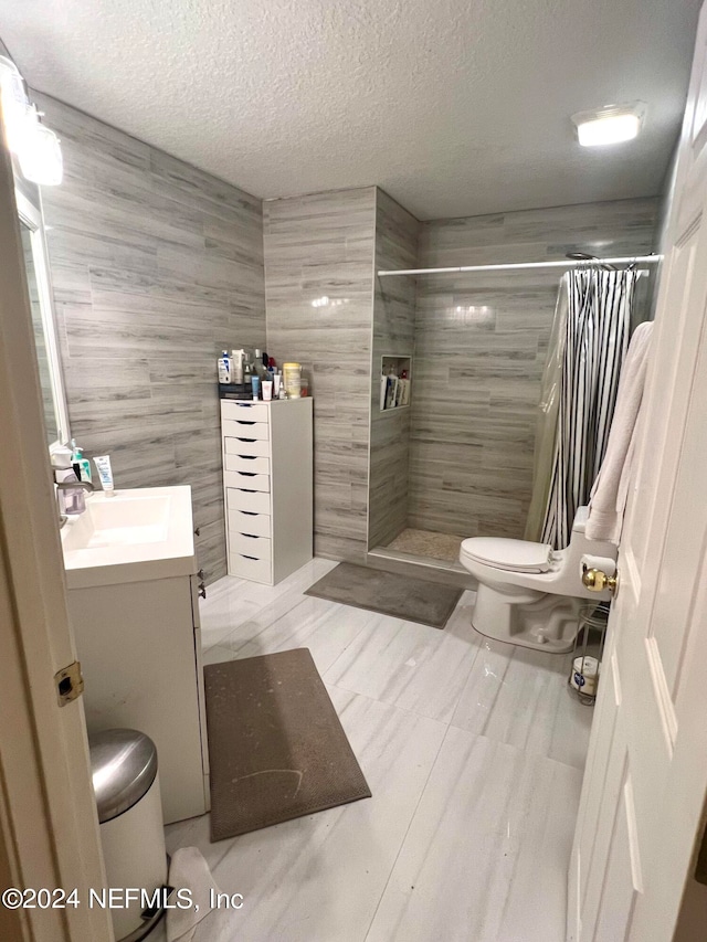 bathroom with vanity, tile patterned floors, curtained shower, tile walls, and toilet