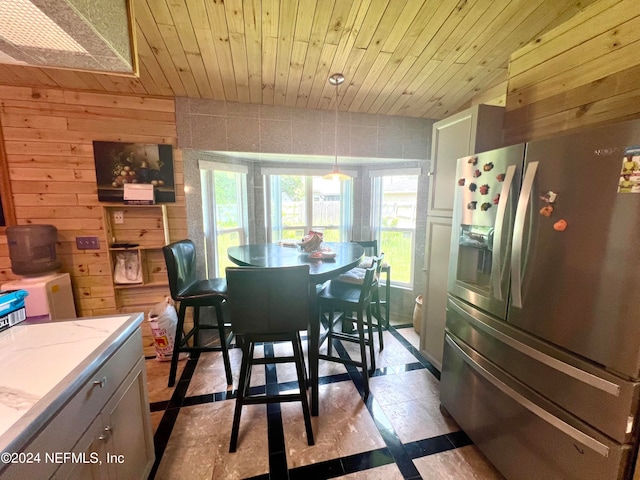 dining room with wood ceiling, wooden walls, and light tile patterned flooring