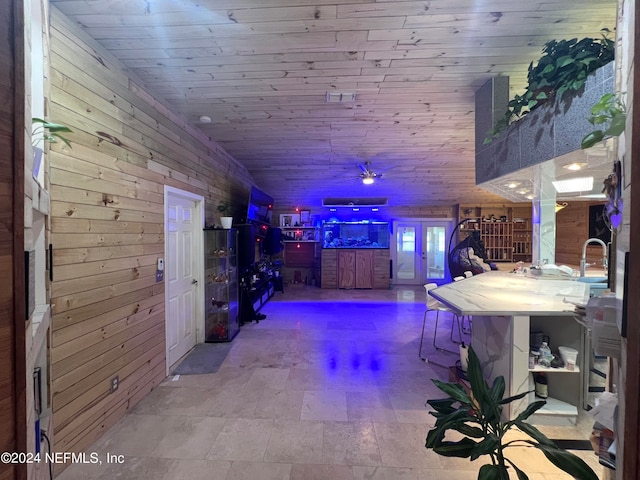 hallway with wood walls, light tile patterned floors, and wooden ceiling