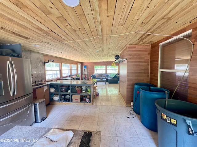 interior space with a wealth of natural light, wooden ceiling, light tile patterned floors, and wood walls