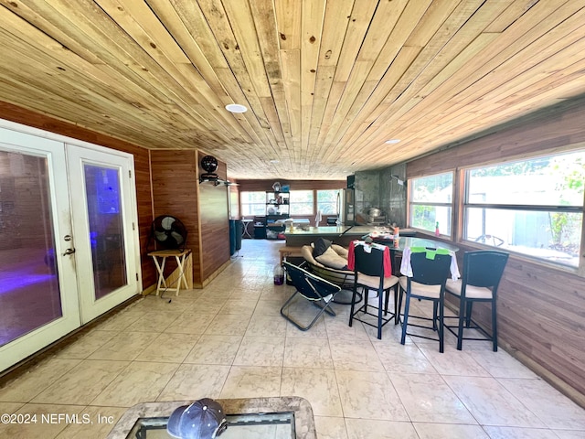 tiled dining room featuring wood walls, french doors, and wood ceiling