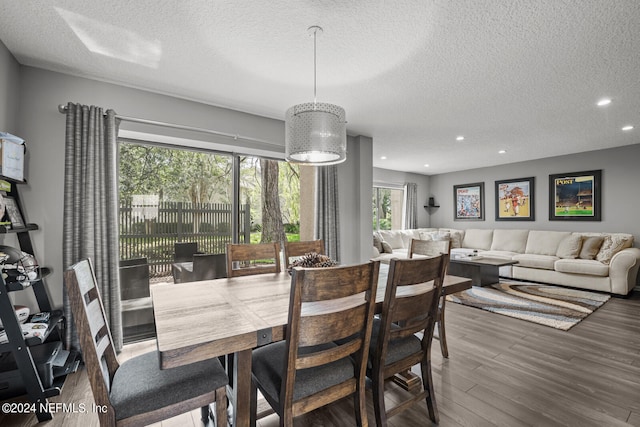 dining room with a textured ceiling, a healthy amount of sunlight, and dark hardwood / wood-style floors