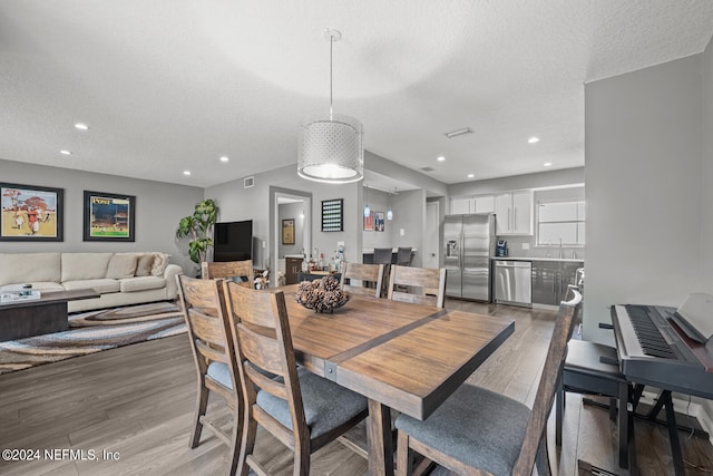 dining room with a textured ceiling, sink, and light hardwood / wood-style floors