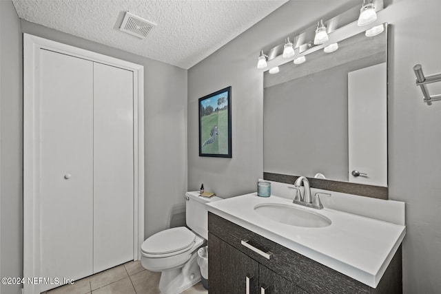 bathroom with a textured ceiling, vanity, toilet, and tile patterned floors