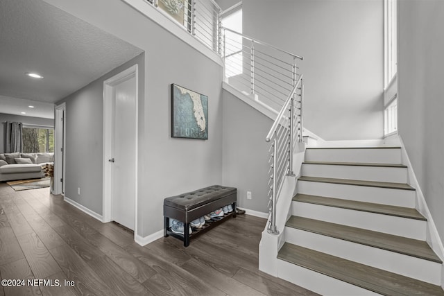 stairs with wood-type flooring and a towering ceiling