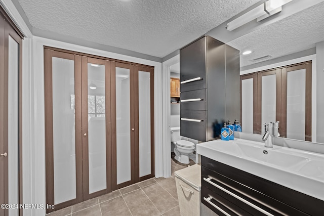 bathroom featuring tile patterned flooring, vanity, toilet, and a textured ceiling