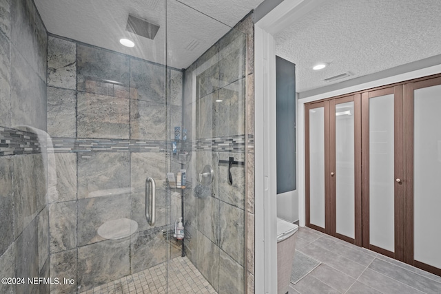 bathroom with tile patterned floors, a textured ceiling, and a shower with shower door