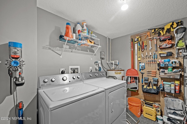 clothes washing area with a textured ceiling, electric water heater, and washing machine and clothes dryer