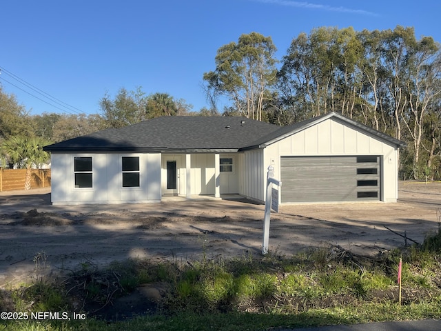 view of front of property with a garage, roof with shingles, board and batten siding, and fence