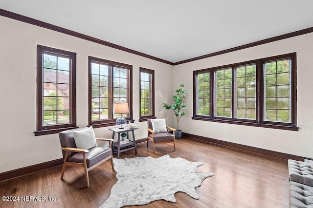 sitting room featuring hardwood / wood-style floors, crown molding, and a healthy amount of sunlight