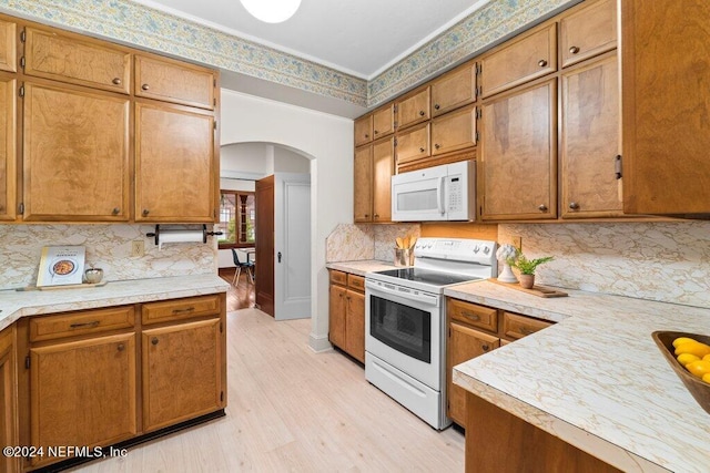 kitchen with crown molding, white appliances, tasteful backsplash, and light hardwood / wood-style floors