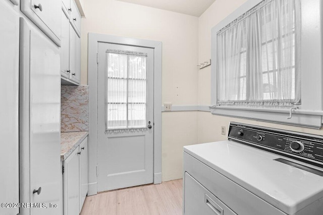 washroom with washer / clothes dryer, cabinets, and light hardwood / wood-style floors