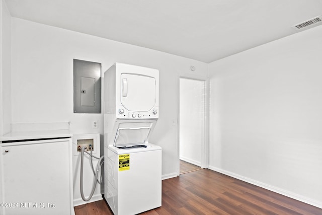 clothes washing area featuring stacked washer / drying machine, hardwood / wood-style floors, and electric panel