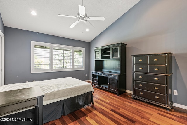 bedroom with dark wood-type flooring, lofted ceiling, ceiling fan, and a textured ceiling