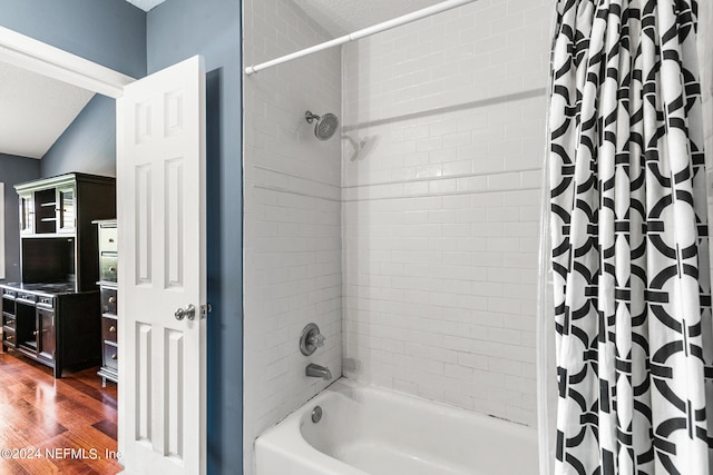 bathroom with a textured ceiling, hardwood / wood-style floors, and shower / bathtub combination with curtain