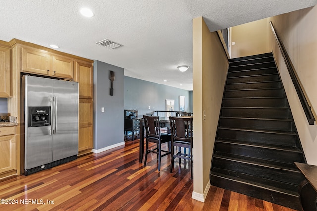 interior space with stainless steel fridge, dark hardwood / wood-style flooring, light brown cabinets, and a textured ceiling