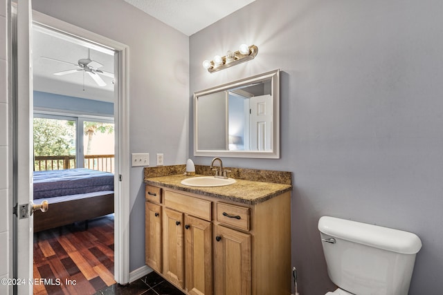 bathroom featuring wood-type flooring, toilet, vanity, and ceiling fan