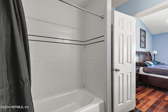 bathroom with vaulted ceiling, shower / tub combo with curtain, and wood-type flooring