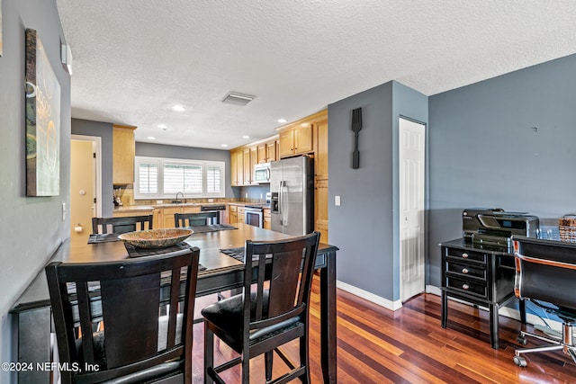 dining area with a textured ceiling, sink, and dark hardwood / wood-style floors