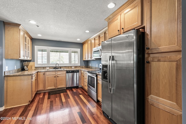 kitchen with light stone counters, stainless steel appliances, sink, dark hardwood / wood-style floors, and a textured ceiling