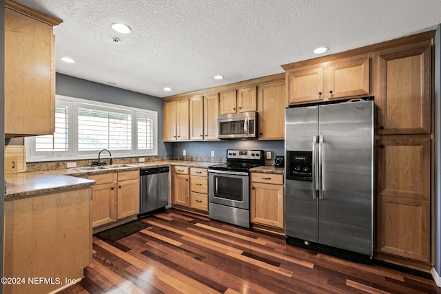 kitchen with appliances with stainless steel finishes, dark hardwood / wood-style flooring, sink, and a textured ceiling