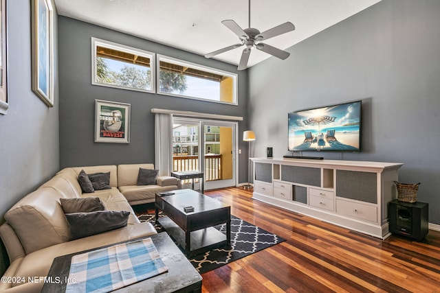 living room featuring a high ceiling, ceiling fan, and wood-type flooring