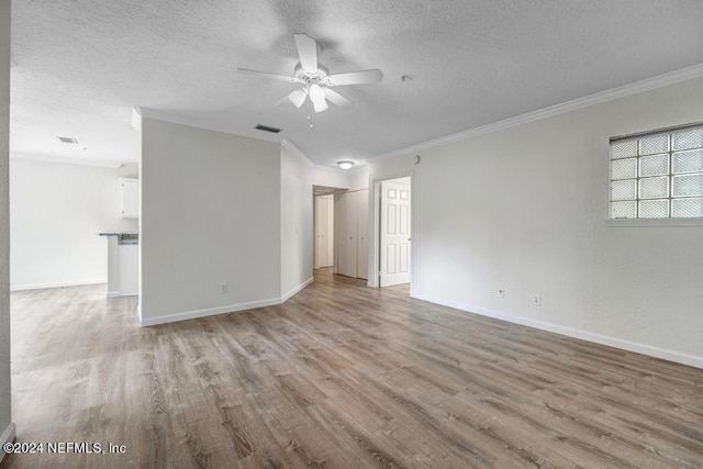 empty room featuring baseboards, visible vents, light wood-style flooring, and a textured ceiling