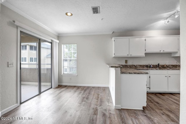 kitchen with light wood finished floors, visible vents, white cabinetry, and a textured ceiling