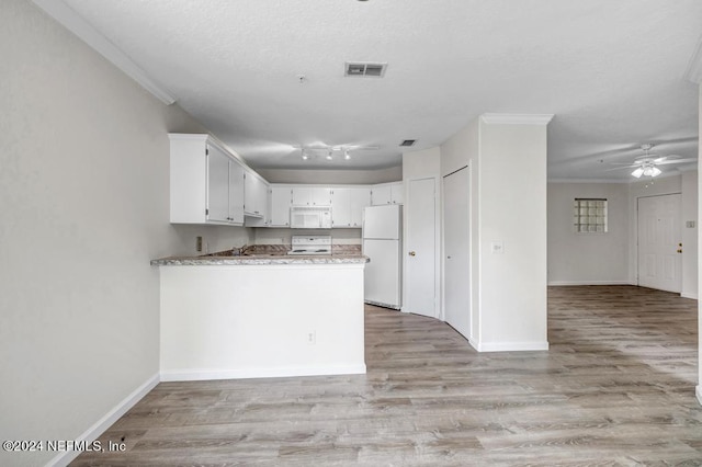 kitchen with a peninsula, white appliances, visible vents, and white cabinetry