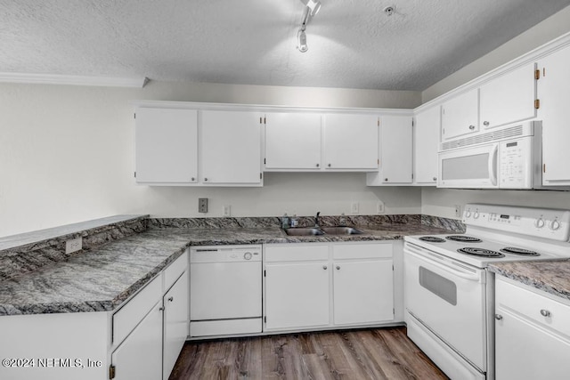 kitchen featuring white appliances, dark countertops, a sink, and white cabinetry