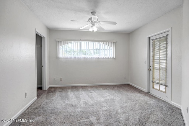 carpeted empty room featuring a ceiling fan, a textured wall, a textured ceiling, and baseboards