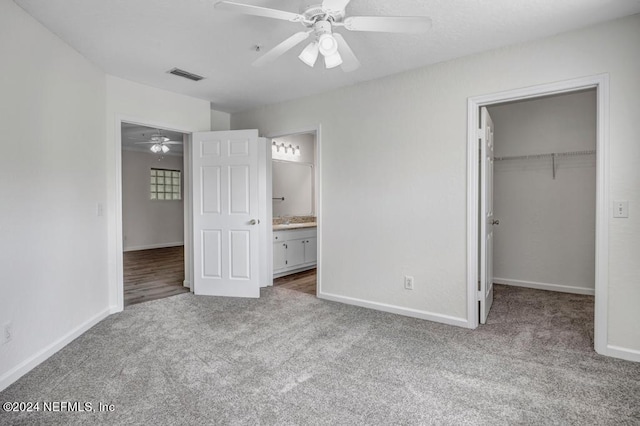 unfurnished bedroom with carpet, a walk in closet, a closet, visible vents, and baseboards