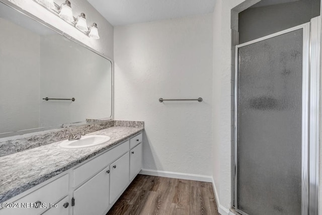 bathroom with a shower stall, baseboards, wood finished floors, and vanity