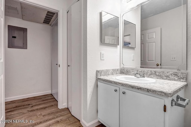 bathroom featuring electric panel, baseboards, wood finished floors, and vanity