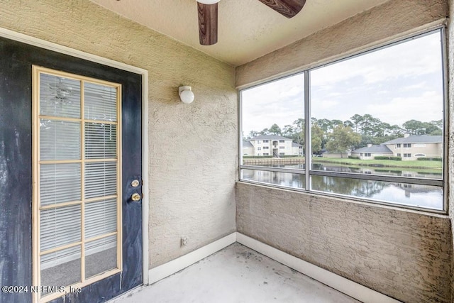 view of exterior entry featuring a water view, a balcony, and ceiling fan