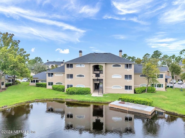 exterior space featuring a water view, stairs, a chimney, and a lawn