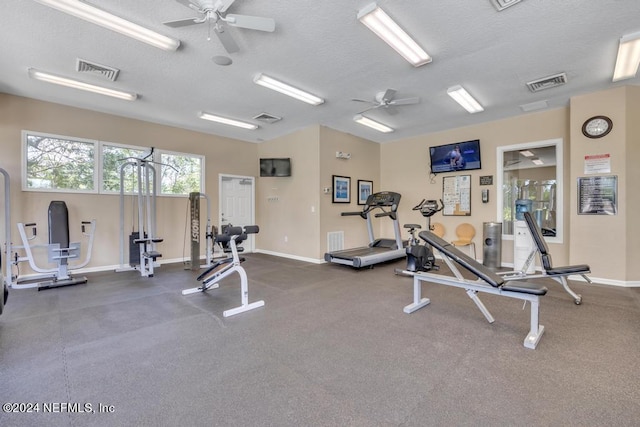 workout area featuring a ceiling fan, baseboards, visible vents, and a textured ceiling