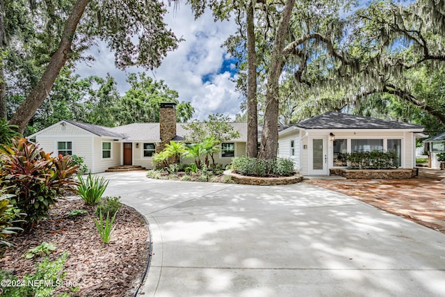 ranch-style home with concrete driveway and a chimney