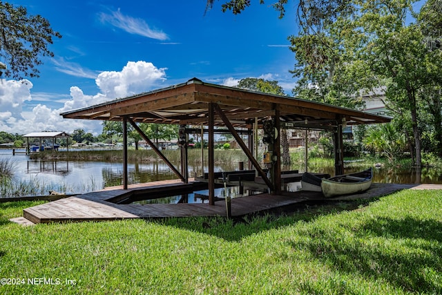 dock area featuring a water view, a yard, and boat lift