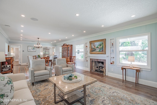 living area featuring crown molding, an inviting chandelier, a brick fireplace, a textured ceiling, and wood finished floors